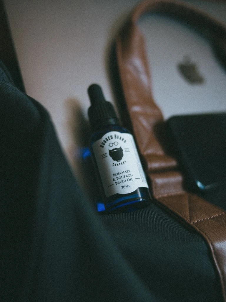 Beard oil in amber glass bottle with wood comb on walnut.